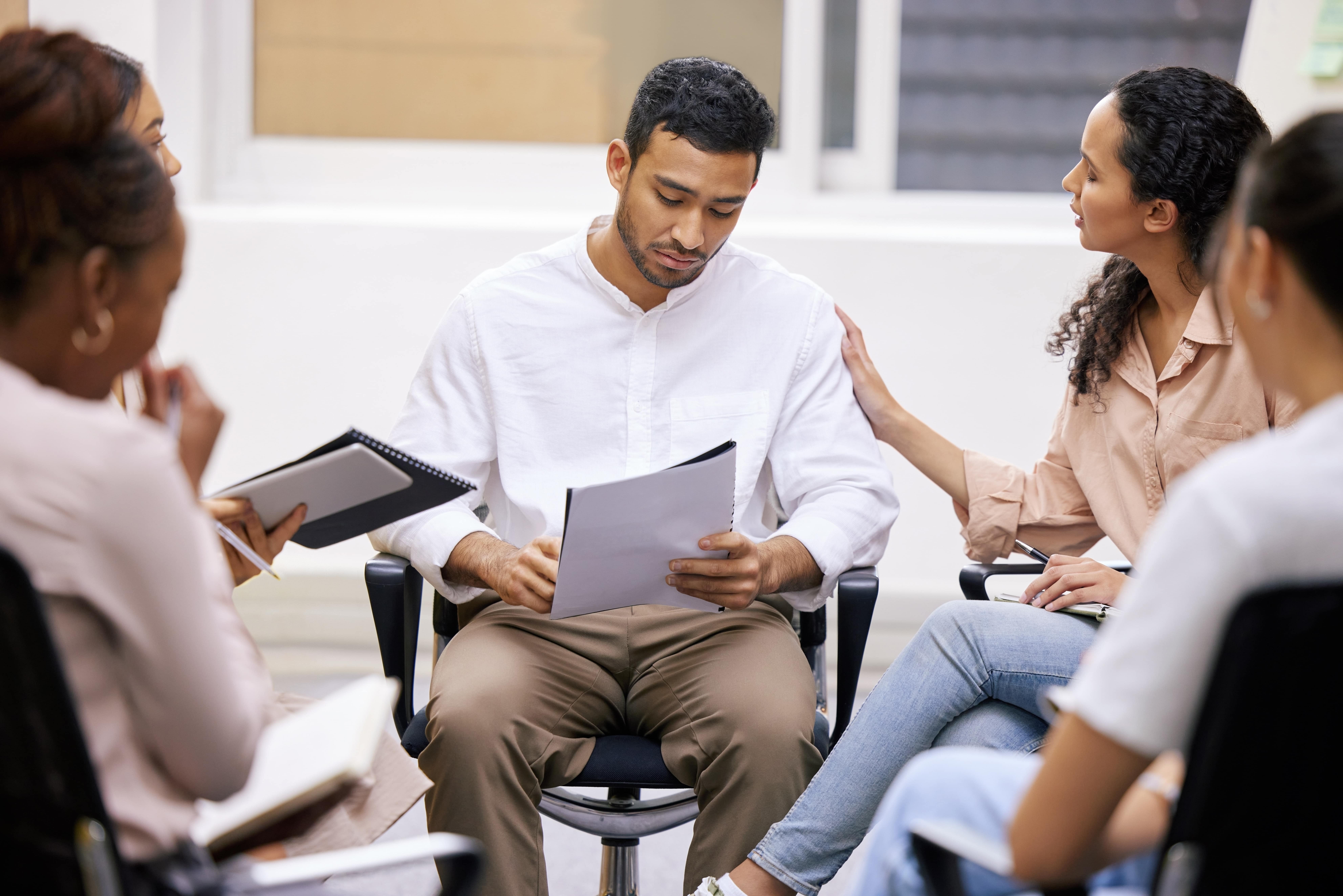 Man seated with a group of people, representing a mediation discussion in a Texas family law case.